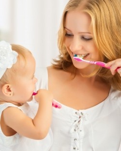 Mutter und Baby üben gemeinsam das Zähneputzen