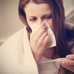 kranke Mutter putzt sich die Nase und misst Fieber