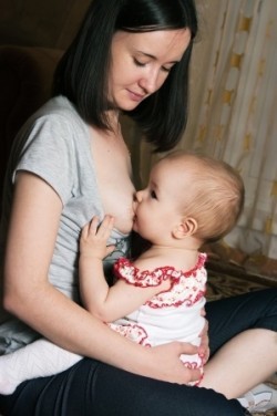 Mutter stillt ihr Baby im Hoppe-Reiter-Sitz