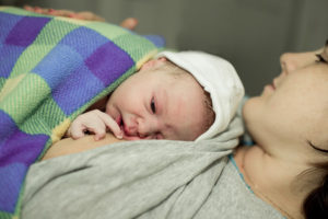 Neugeborenes Baby auf der Brust der Mutter unter einer dicken Decke